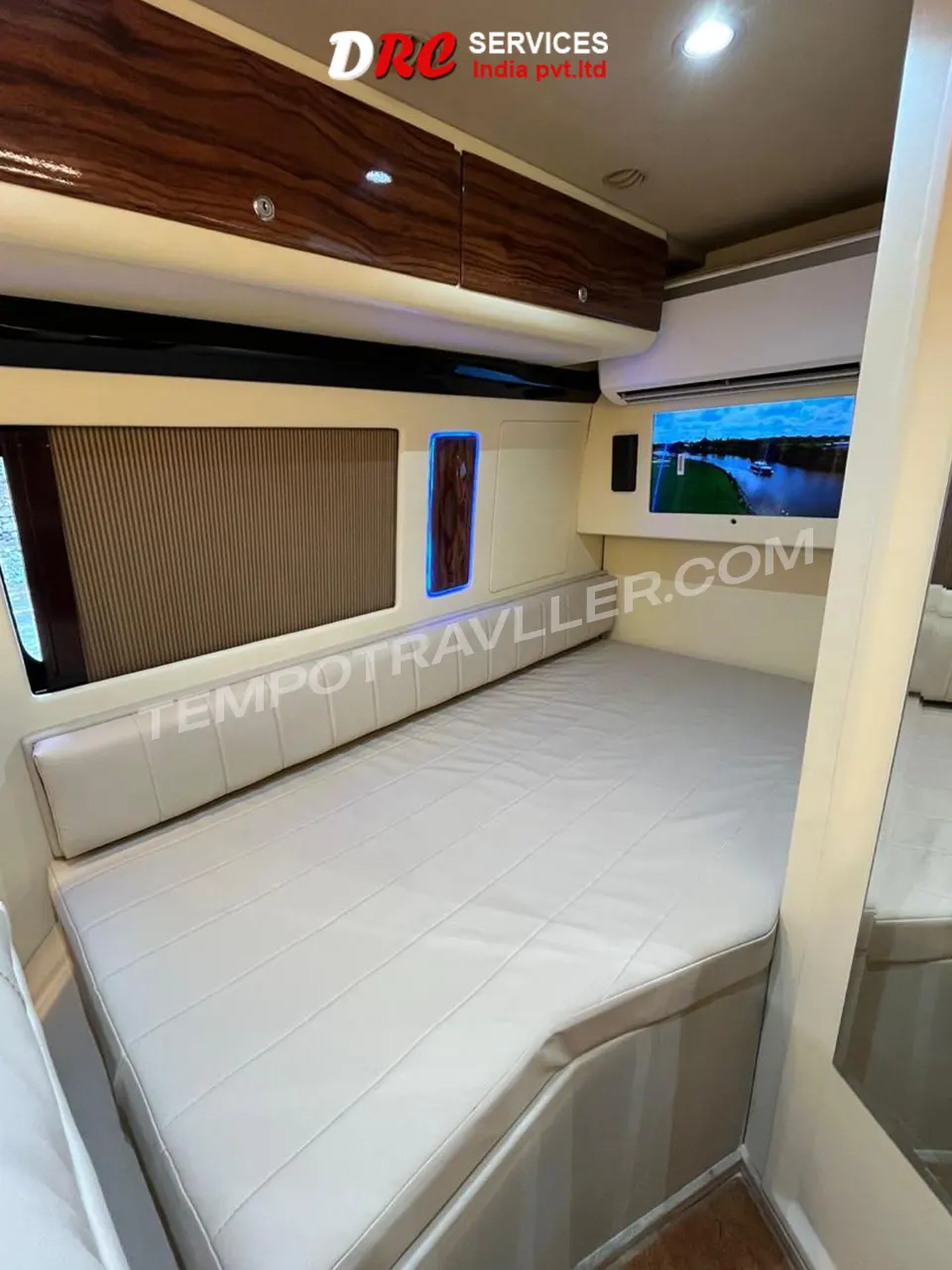 Luxury motorhome bedroom interior with spacious bed, premium upholstery, ambient LED lighting, and overhead storage cabinets.