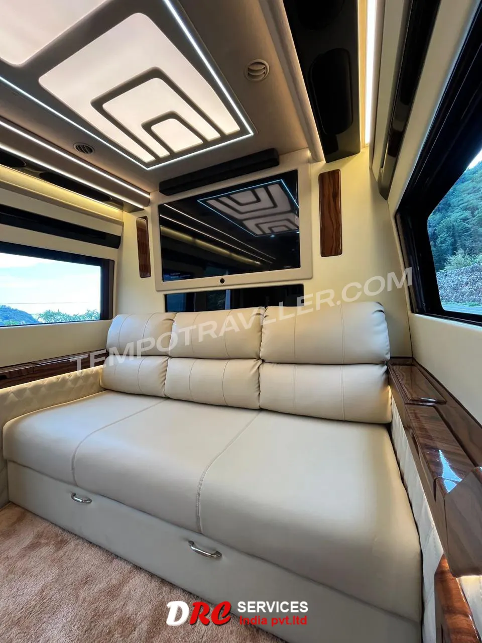 Luxury motorhome interior with sofa bed seating, entertainment screen, ambient LED lighting, and modern ceiling design.